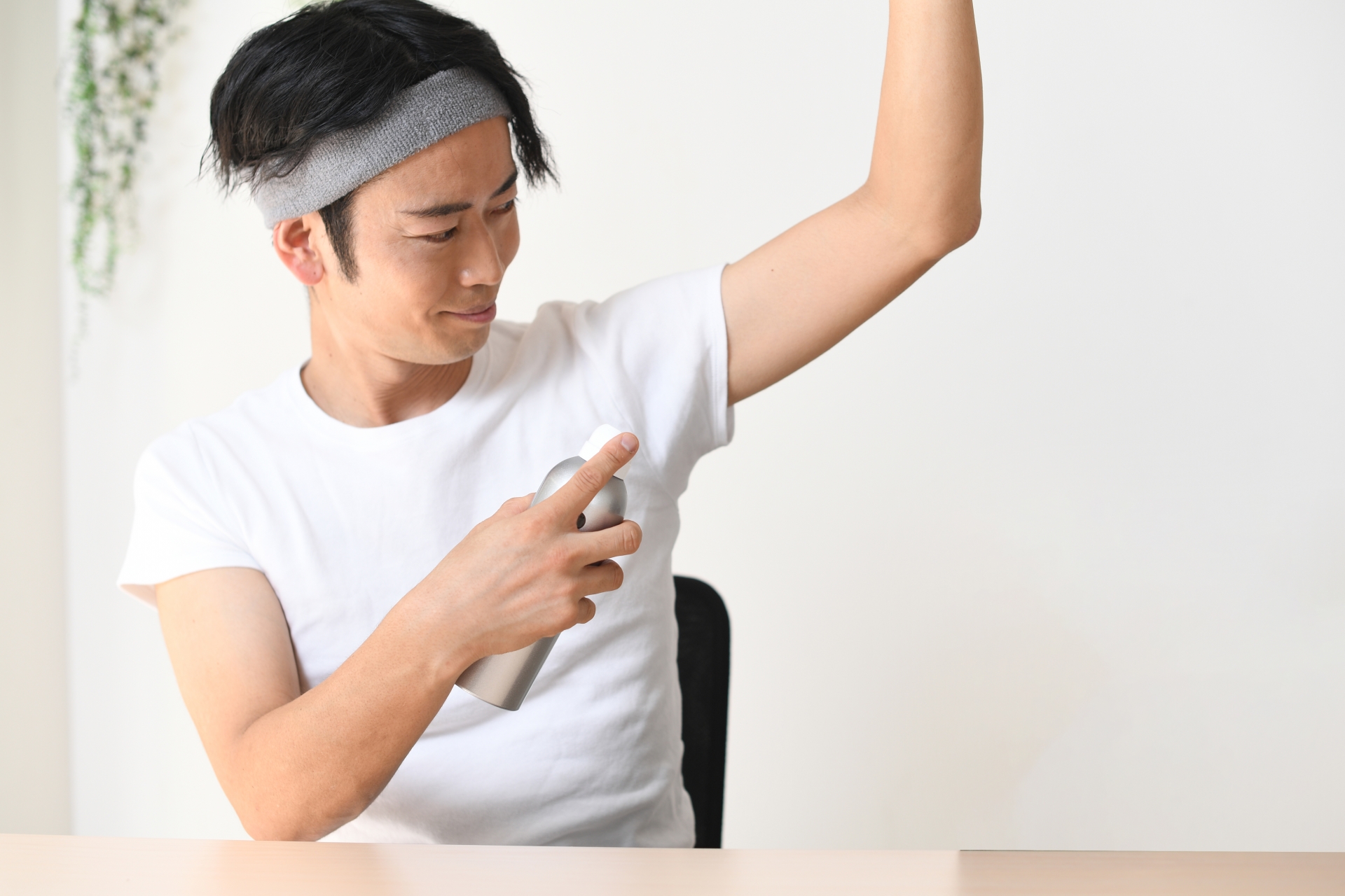 脇に制汗スプレーをする男性