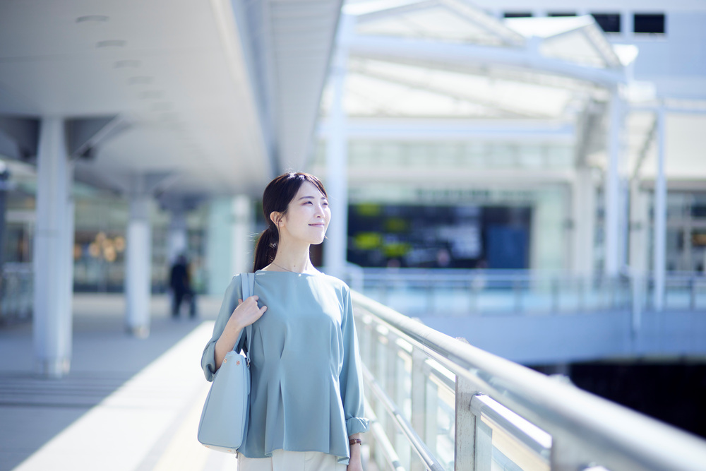 女性が駅前でほほ笑んでいる画像