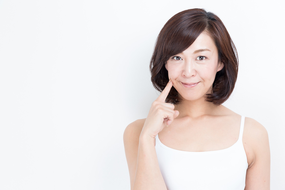 頬を指さす女性