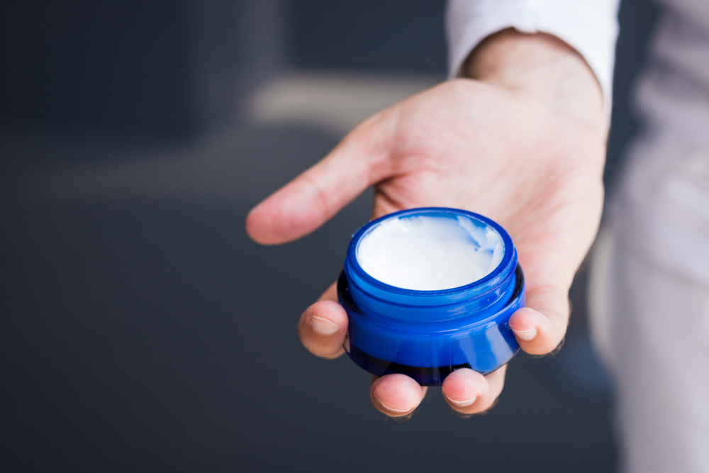 保湿剤を持つ男性