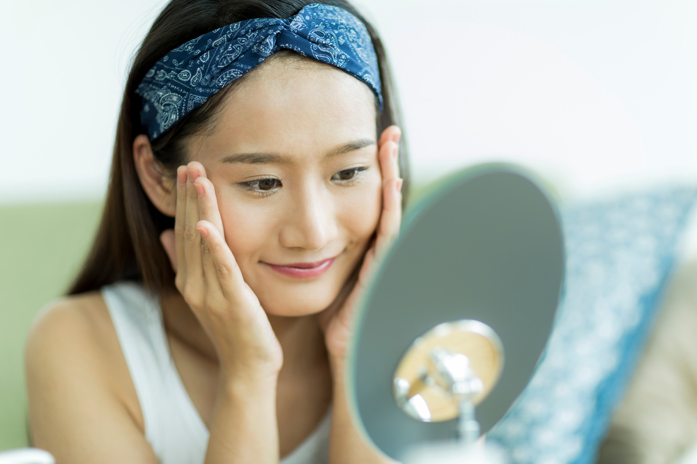 鏡を見て微笑む女性