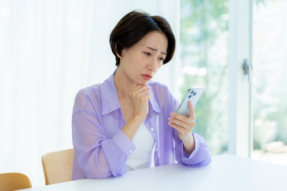 スマホを見て悩む女性