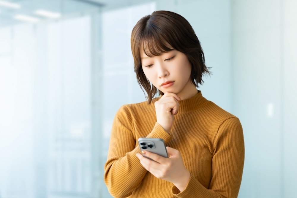 スマホを見て悩む女性