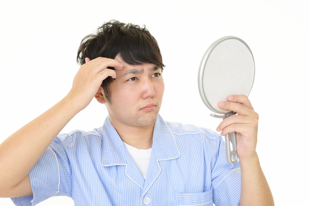 鏡を見て不満そうな男性