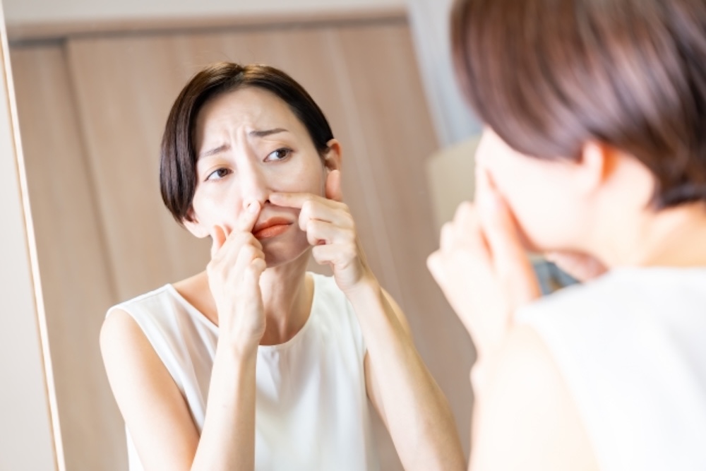 鏡を見て角栓を押し出す女性