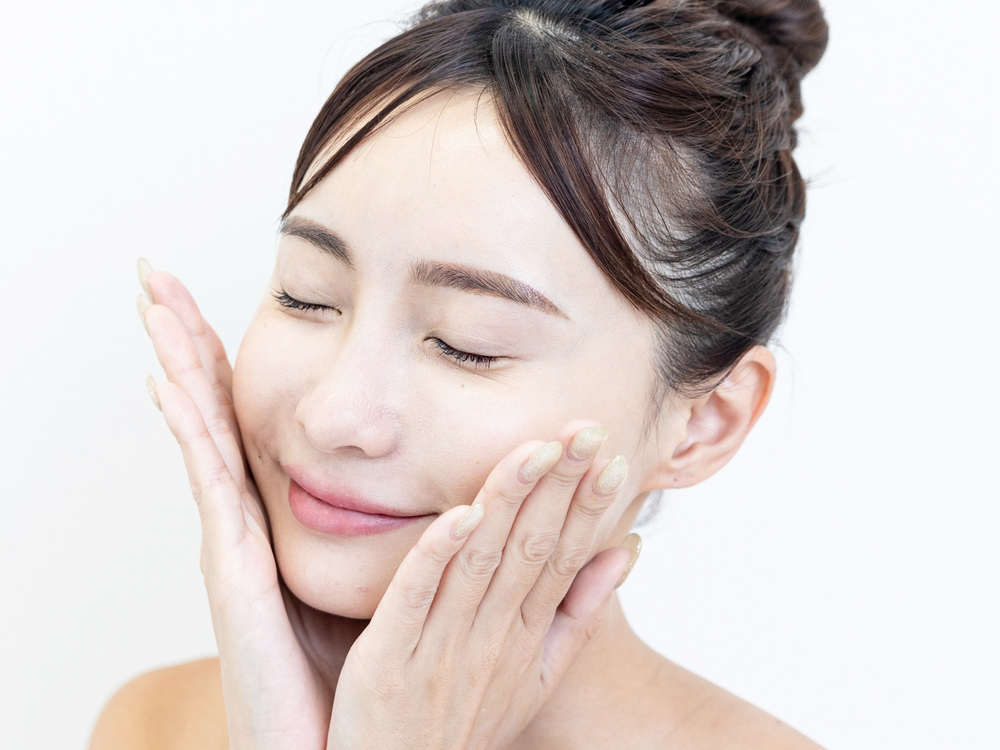 顔に手を当てる脱毛前の女性